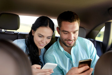 man and woman with smartphones driving in car