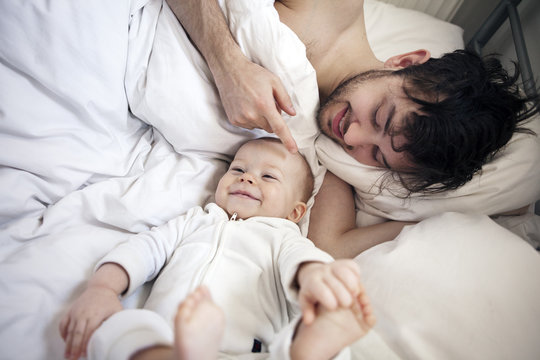 Father with baby boy lying on bed