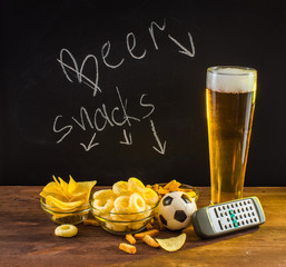 Beer concept. Glass beer and snack to beer on a wooden table on a background of black plank with the inscription.