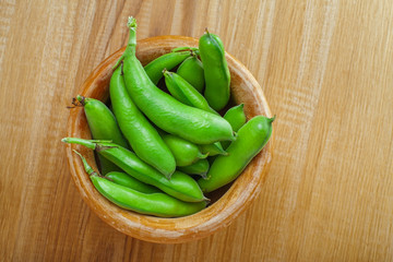 Bowl of fresh podded broad beans on a wooden table. Healthy organic food.