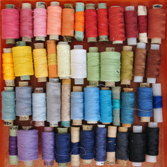 Lots of colorful spools of thread for sewing laid out by color. Top view, background.