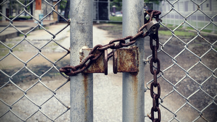 Padlock with rusty iron chain on fence