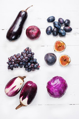 Collection of fresh purple fruit and vegetables on wooden background