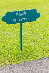 Wooden sign NO ENTRY in green grass garden