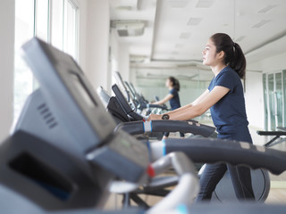 Fototapeta na wymiar Asian woman walking, running on treadmill gym workout.