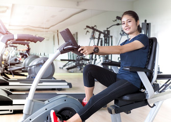 Fototapeta na wymiar Asian woman riding stationary bike in gym.