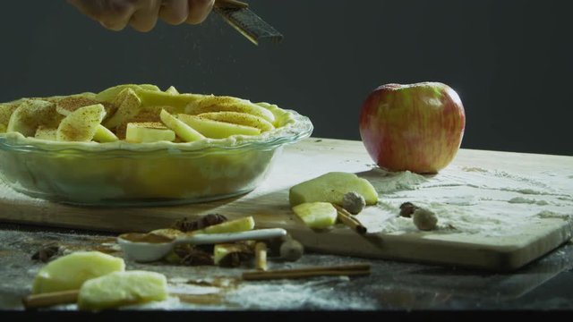 Grating cinnamon onto sliced apples to make apple pie