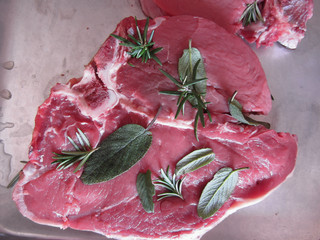 Fresh raw marbled meat steak with sage and rosemary ready to be cooked in the oven