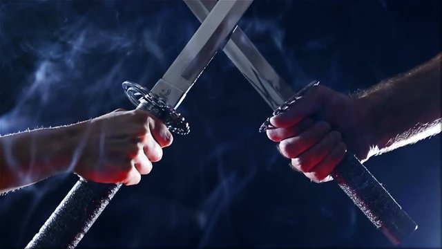 Japanese samurai warriors fighting with swords. Sword battle. Two Japanese katana sword. Blade close-up on a dark background with blue light filter with incense smoke. Steel tempering