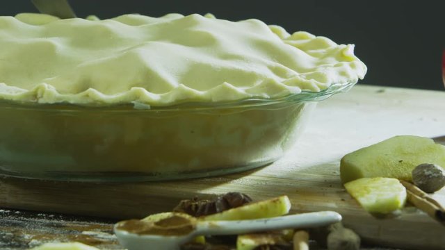 Pan up to knife cutting into apple pie