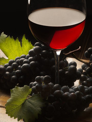 Obrazy na Plexi  Kieliszek z czerwonym winem i winogronem na drewnianym stole