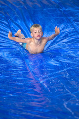 Young boy sliding down a slip and slide outdoors