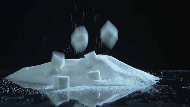 Cubes of sugar dropping into a pile of sugar