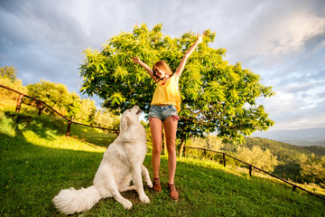 Young and happy woman playing with Maremma italian sheepdog on the lawn in the countryside in Tuscany