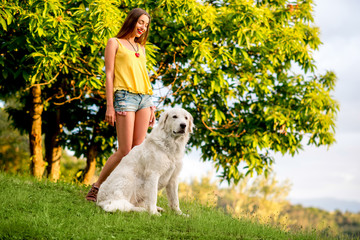 Naklejka na ściany i meble Young and happy woman playing with Maremma italian sheepdog on the lawn in the countryside in Tuscany
