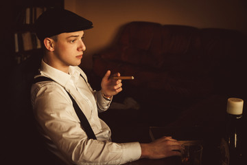 Thoughtful man in black hat looks far away while smoking a cigar