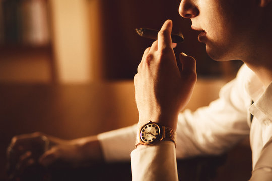Closeup of old-fashioned watch on the hand of man smoking a ciga