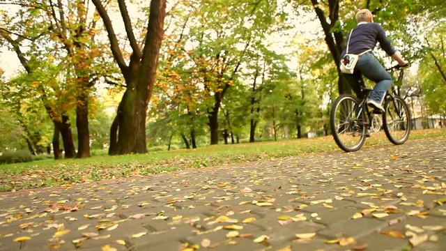 woman riding on bike in autumn setting– hd video