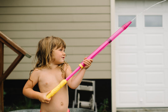 Young girl squirting water from a water hose 