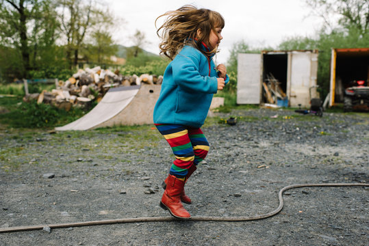 Young child jumping over a hosepipe 