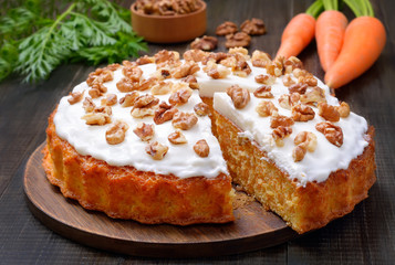 Carrot cake and fresh carrot on wooden table