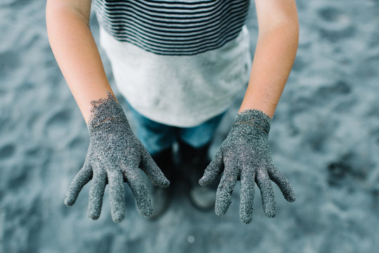 Childs hands outstretched covered in sand 