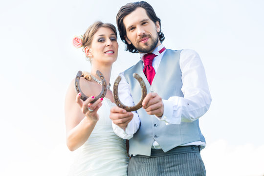 Wedding couple showing horse shoe for luck