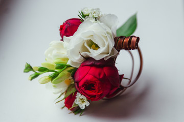 Boutonniere made of dark rose and white flower lies on the table