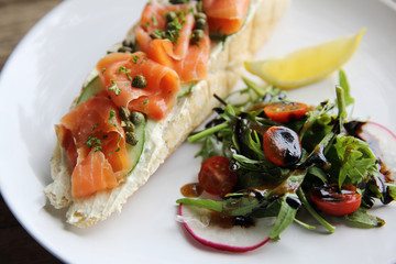 smoked salmon on toasted bread with cream fresh, lemon and salad
