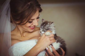 Bride with charming smile holds sleepy kitten in her arms