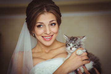 Radiant bride smiles while holding little kitten in her arms