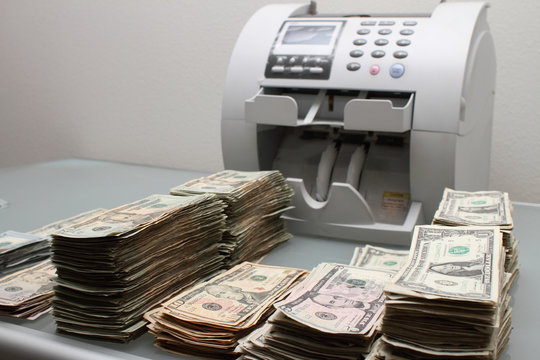 Stacks of cash next to a money counting machine.