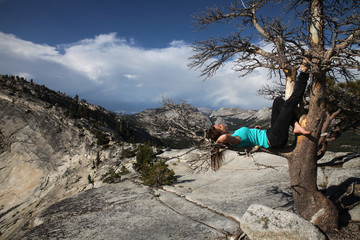 Woman lying on a tree at Olmsted Point, Tuolumne, Yosemite, California, USA