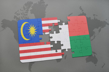 puzzle with the national flag of malaysia and madagascar on a world map background.