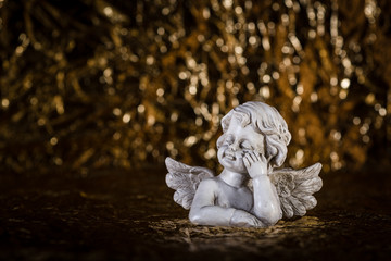 Trauriger, betender oder verträumter Engel auf Hintergrund schwarz gold für Trauer oder Schutzengel Konzepte.