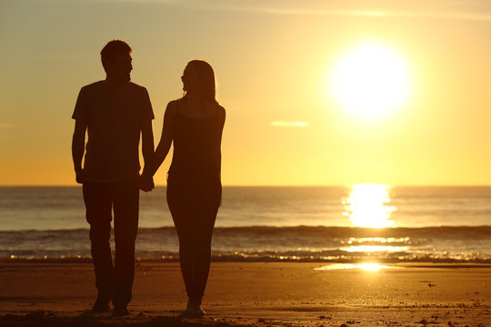 Couple silhouette walking together on the beach