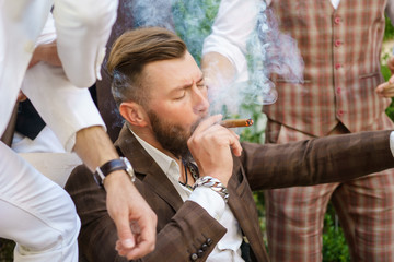 Handsome young guy with closed eyes enjoying cigar