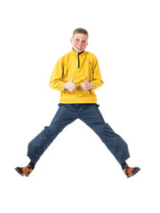 Young red-haired boy in a yellow jacket jumping boy with hands clenched in a fist and raised his thumb up on a white background