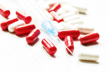 Drug in red and white capsules, empty syringe for injections on