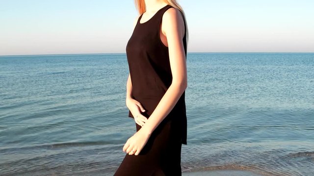 beautiful girl model walks on the shore beach. the wind, the sea breeze develops hair romantic sexual young woman, girl look love looking at the camera, weekend by the sea, beautiful sea calm