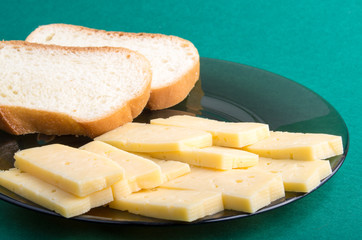 Plate on a green background with cheese slices and pieces of bre