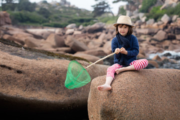 thinking young child holding a fishing net to discover nature