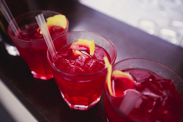 Beautiful row line of different colored alcohol cocktails on a party, martini, vodka,and others on decorated catering bouquet table on open air event, picture with beautiful bokeh
