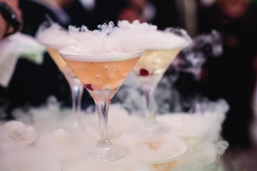 Beautiful row line of different colored alcohol cocktails on a party, martini, vodka,and others on decorated catering bouquet table on open air event, picture with beautiful bokeh
