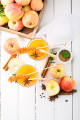 Spiced apple cider with star anise and cinnamon on white wood table, top view
