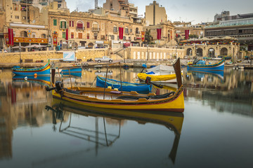 St.Julian's, Malta - Traditional colorful Luzzu fishing boats at Spinola bay at sunrise - obrazy, fototapety, plakaty