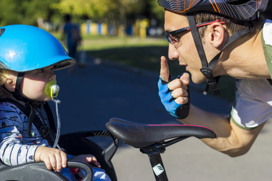 Father and son riding at the bicycle with bike chair