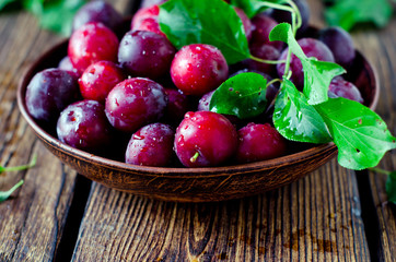 Fresh plums in a bowl on a wooden table