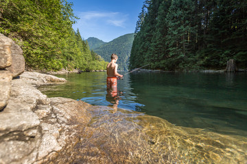 Boy fishing in the middle of river on a warm sunny day