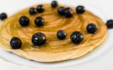 Close up of a tasty american pancake with blueberries and maple syrup. Selective focus.